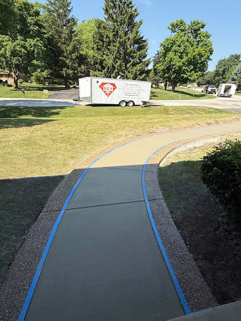 Sidewalk and walkway with exposed aggregate border and white broomed concrete finish